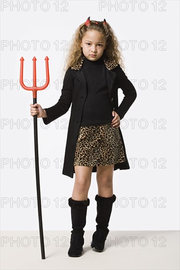 Studio portrait of girl (8-9) wearing Halloween costume with trident. Photo: Rob Lewine