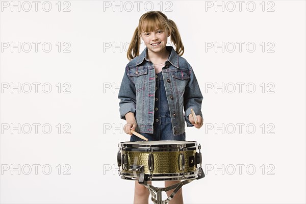 Studio portrait of girl (8-9) playing drums. Photo: Rob Lewine