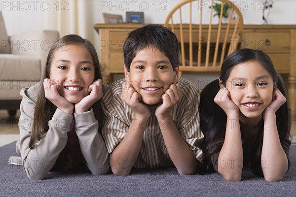 Portrait of smiling siblings (8-9, 10-11) lying on floor. Photo : Rob Lewine