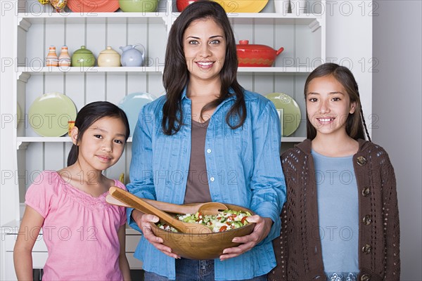 Portrait of mother with two daughters (8-9, 10-11) in kitchen. Photo : Rob Lewine