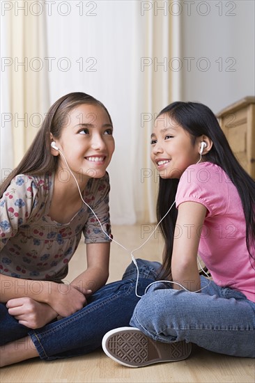 Sisters (8-9, 10-11) listening together music on headphones. Photo : Rob Lewine