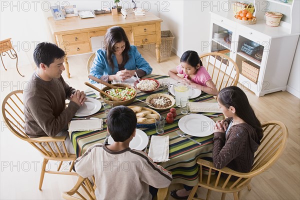 Family with three children (8-9, 10-11) praying at table before dining. Photo : Rob Lewine