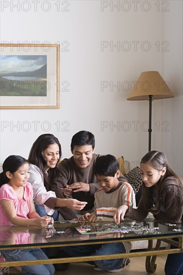 Family with three children (8-9, 10-11) playing with puzzle. Photo : Rob Lewine