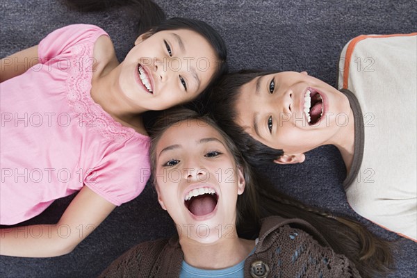 Portrait of laughing children (8-9, 10-11) lying on floor. Photo: Rob Lewine