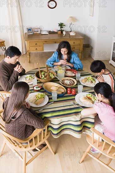 Family with three children (8-9, 10-11) praying at table before dining. Photo : Rob Lewine