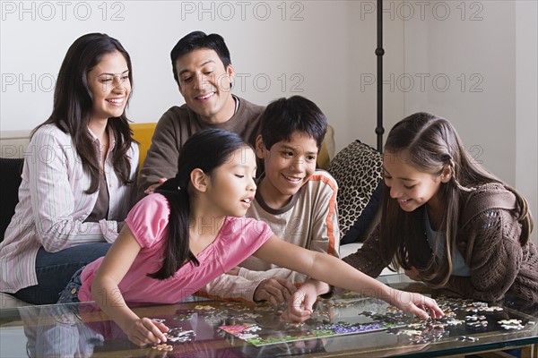 Family with three children (8-9, 10-11) playing with puzzle. Photo: Rob Lewine