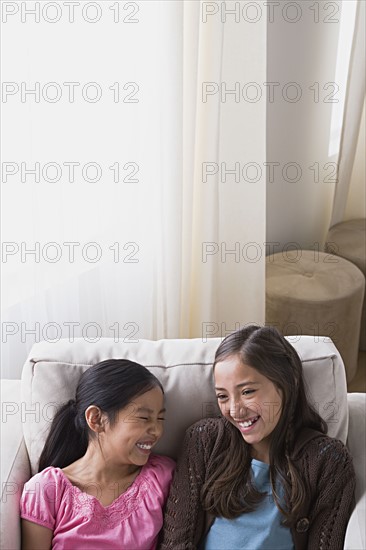 Sisters (8-9, 10-11) laughing in armchair. Photo: Rob Lewine