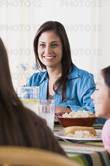 Smiling woman dining with daughters (8-9, 10-11). Photo : Rob Lewine