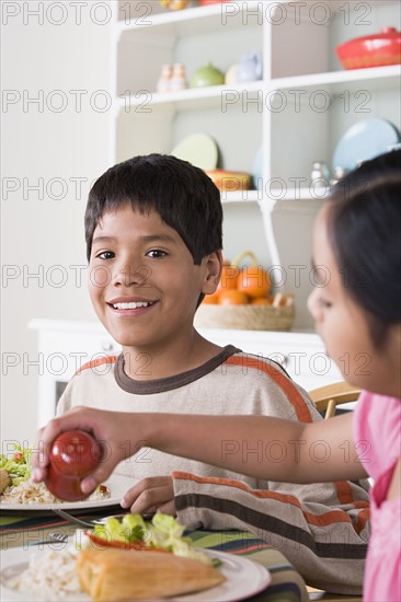 Portrait of smiling boy (10-11) and girl (8-9) dining at table. Photo : Rob Lewine