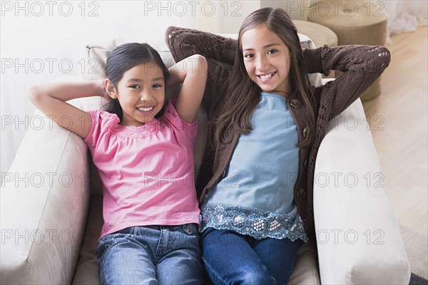 Portrait of smiling girls (8-9, 10-11) in armchair. Photo: Rob Lewine