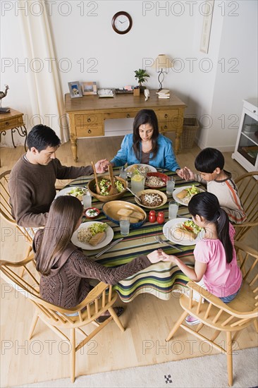 Family with three children (8-9, 10-11) praying at table. Photo : Rob Lewine