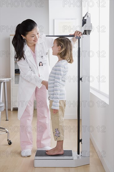 Female doctor measuring girl (4-5). Photo : Rob Lewine