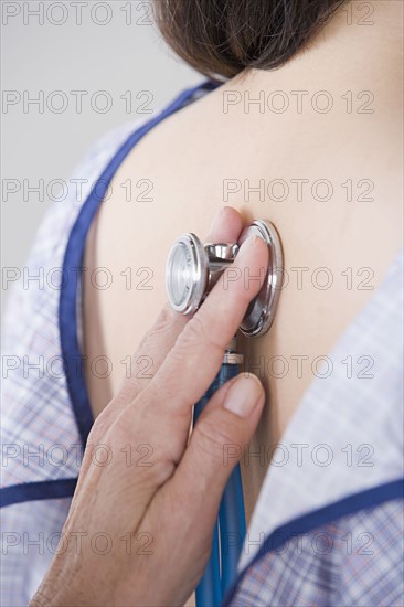 Close up of doctor's hand examining woman with stethoscope. Photo : Rob Lewine