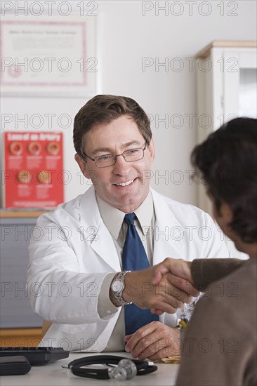 Smiling male doctor shaking hand with patient in his office. Photo : Rob Lewine