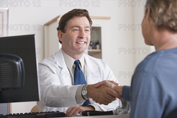 Male doctor shaking hand with patient. Photo : Rob Lewine