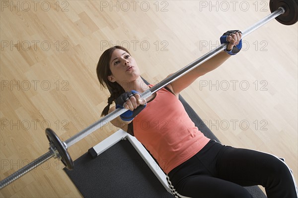 Woman lifting barbell in gym. Photo : Rob Lewine