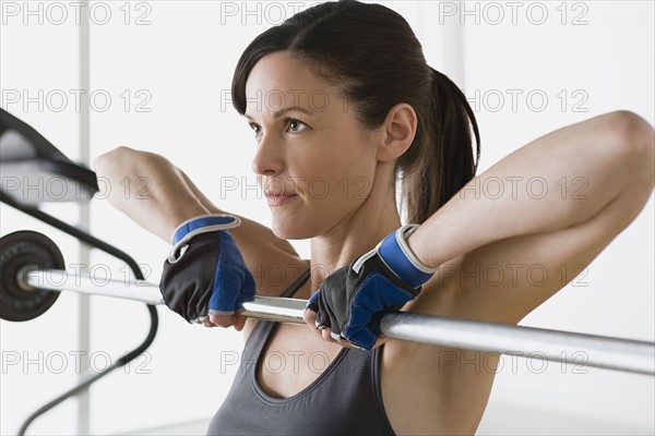 Woman lifting barbell in gym. Photo : Rob Lewine