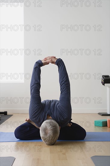 Mature man practicing yoga on mat. Photo : Rob Lewine