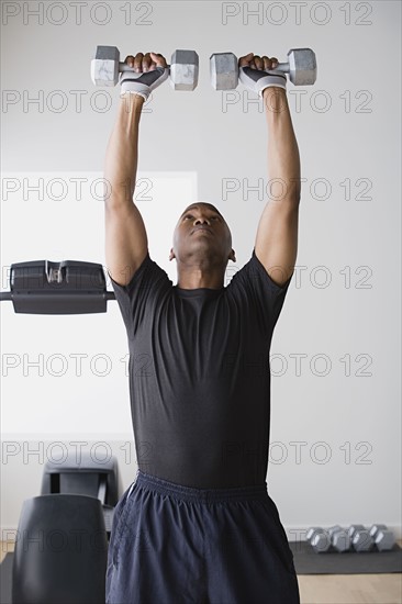 Young man lifting weights in gym. Photo : Rob Lewine