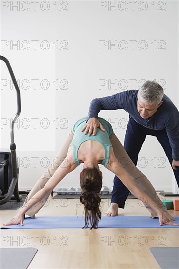 Woman stretching while instructor assisting her. Photo : Rob Lewine
