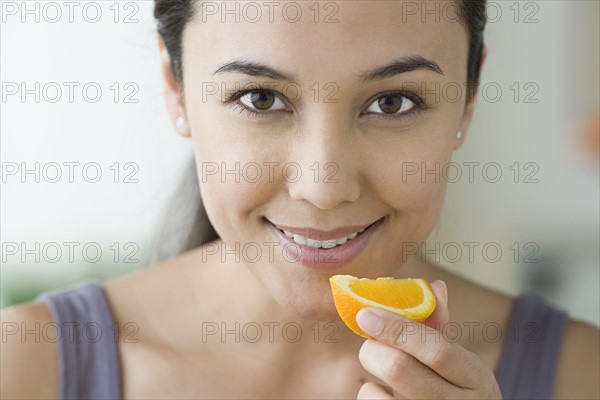 Portrait of attractive woman holding slice of orange. Photo: Rob Lewine
