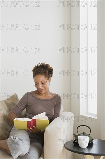 Woman relaxing with book at home. Photo : Rob Lewine