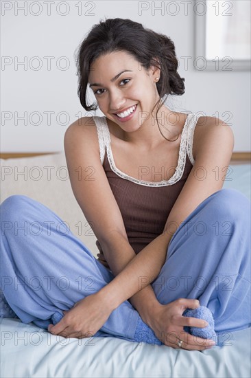Woman sitting on bed. Photo : Rob Lewine