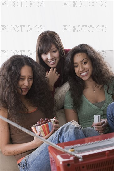Three female friends watching television. Photo: Rob Lewine