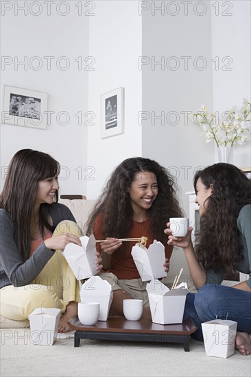 Young women eating take out food at home. Photo : Rob Lewine