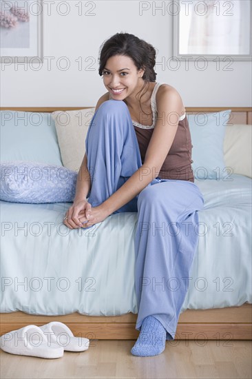 Young woman sitting on bed. Photo : Rob Lewine