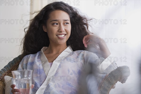 Young woman relaxing in wicker chair. Photo : Rob Lewine