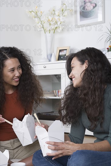Young women eating take out food at home. Photo : Rob Lewine
