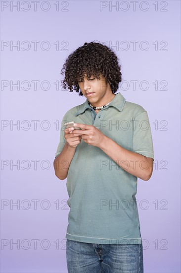 Portrait of teenage boy (14-15) texting on mobile phone. Photo : Rob Lewine