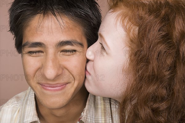 Portrait of teenage (16-17) girl kissing teenage boy (16-17). Photo: Rob Lewine