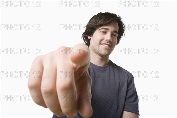 Studio portrait of young man pointing. Photo : Rob Lewine