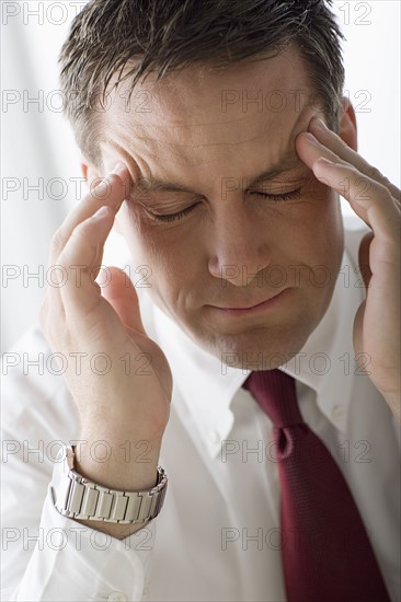 Portrait of businessman touching his head. Photo : Rob Lewine