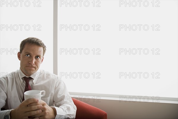 Portrait of businessman sitting with mug. Photo : Rob Lewine