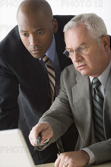 Portrait of two businessmen working on laptop. Photo: Rob Lewine