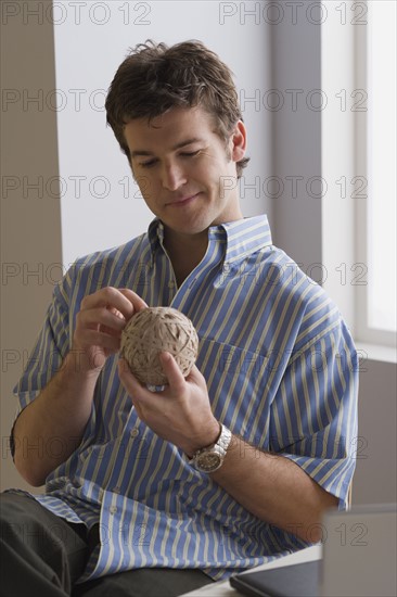 Portrait of businessman with ball of wool. Photo : Rob Lewine