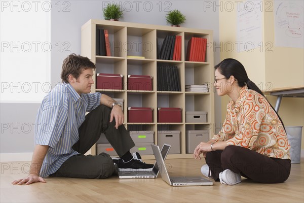 Two office workers sitting on floor with their laptops. Photo : Rob Lewine