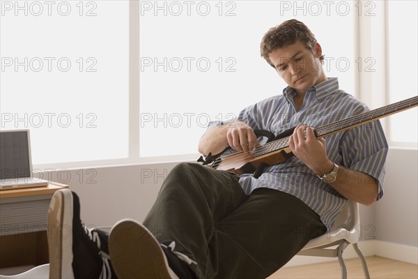 Young man playing electric base guitar. Photo : Rob Lewine