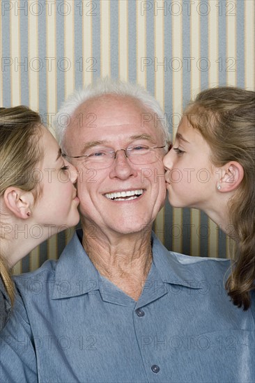 Portrait of two girls (8-9, 14-15) kissing grandfather. Photo: Rob Lewine