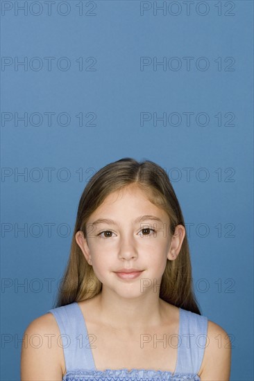 Portrait of happy girl (8-9) n blue background. Photo : Rob Lewine