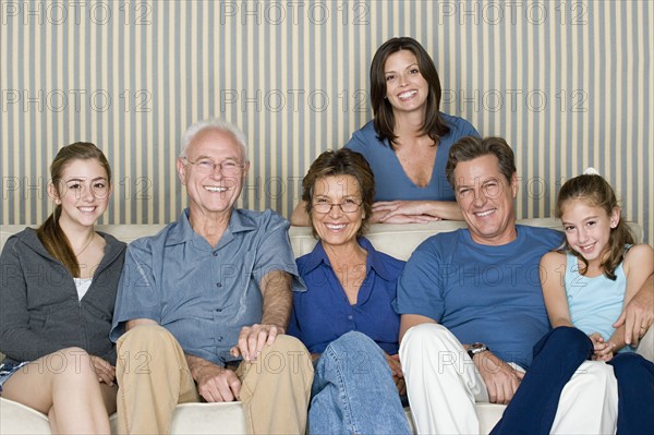 Portrait of two generation family with two girls (8-9, 14-15) sitting on sofa. Photo: Rob Lewine