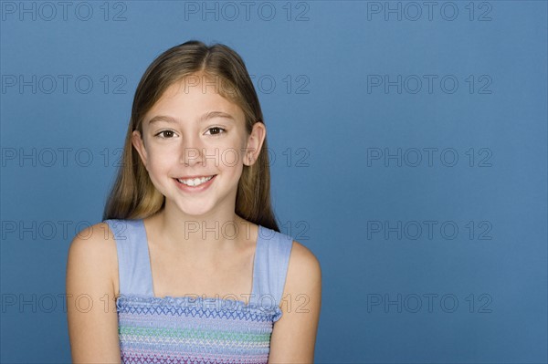 Portrait of happy girl (8-9) n blue background. Photo : Rob Lewine