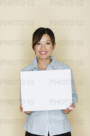 Portrait of happy asian woman holding blank sheet of paper. Photo: Rob Lewine