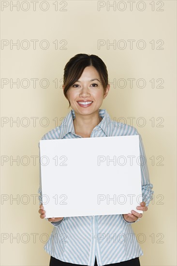 Portrait of happy asian woman holding blank sheet of paper. Photo : Rob Lewine