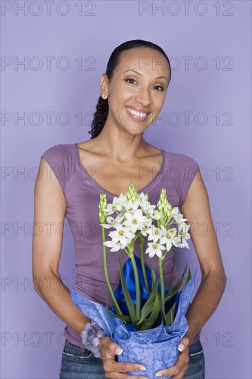 Portrait of happy mid adult african woman holding flower. Photo : Rob Lewine