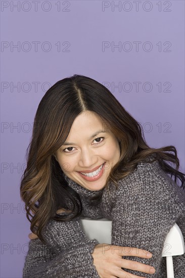 Portrait of smiling woman on purple background, studio shot. Photo : Rob Lewine