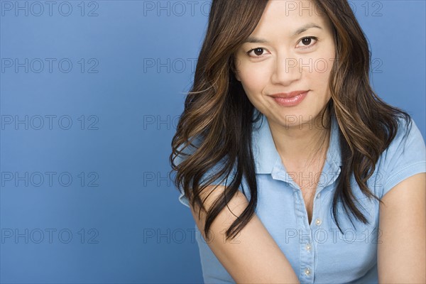 Portrait of smiling woman on blue background, studio shot. Photo : Rob Lewine